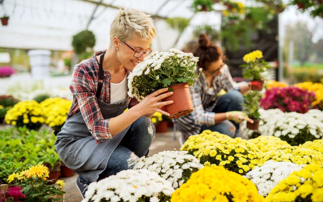 a woman smells some flowers in a garden center